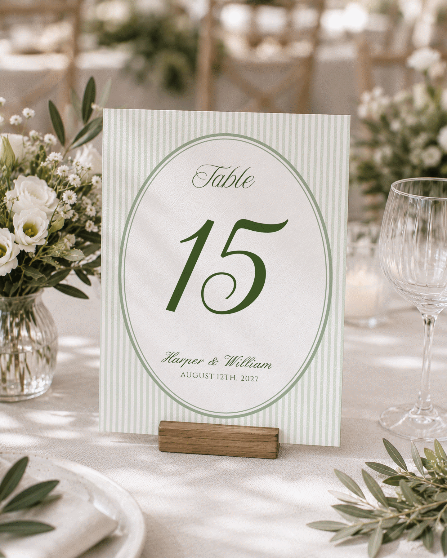 Sage green striped oval table number fifteen in a wedding reception setting